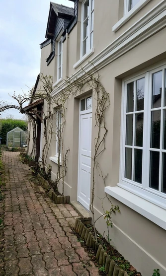 Nachher — Fassade mit Greige (RAL 7044) und Reinweiss auf den Fensterrahmen, Haustuer und Gesimse (Stadtvilla)