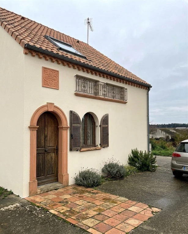 After — facade in White Heron (BM OC-57) with Terra Cotta on the arched doorway frame, balcony railings, courtyard tile, gable accent (Mediterranean Revival)