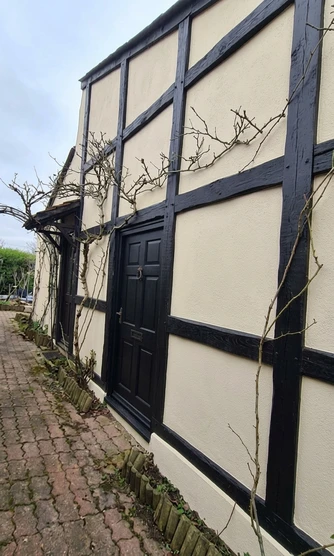 After — facade in Warm Cream (None) with Pitch Black on the exposed timber beams and front door (Country Cottage)