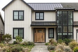 After — facade in Alabaster Warm White (SW 7008) with Tricorn Black + Natural Oak on the trim and wood door (Modern Farmhouse)